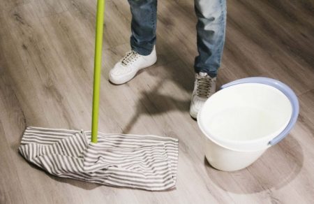 A man cleaning polished floor with bucket and mop in Prairieville, LA