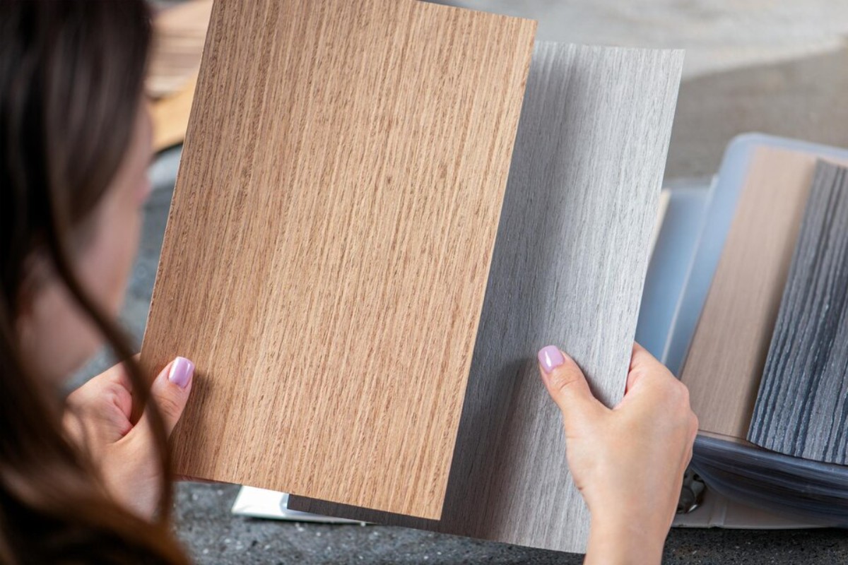 The woman chooses from the designer based on samples of different shades and colors for the best flooring for a cold room.